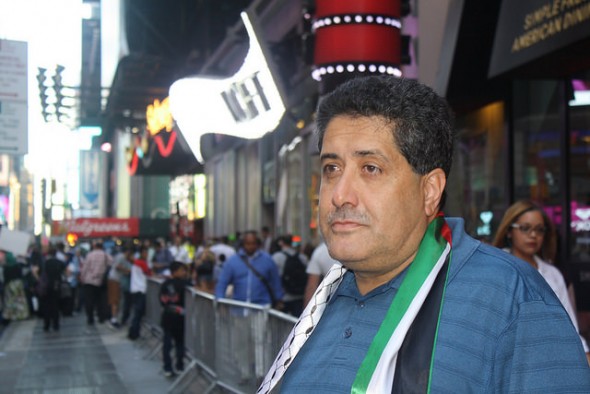 Diab Mustafa, President of the Palestinian American Community Center, stands at the back of the demonstration, wearing a Palestinian flag. Photo by Wyatt Salsbury