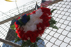 An American flag and order of flowers hung on a fence outside of the World Trade Center Site. Photo by Brelaun Douglas.