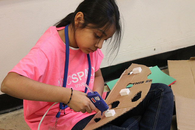 Pamela Flores, 11, uses a hot glue gun to put together a backdrop for an "Angry Birds" project at NYC Sparx. Photo by Karis Rogerson.