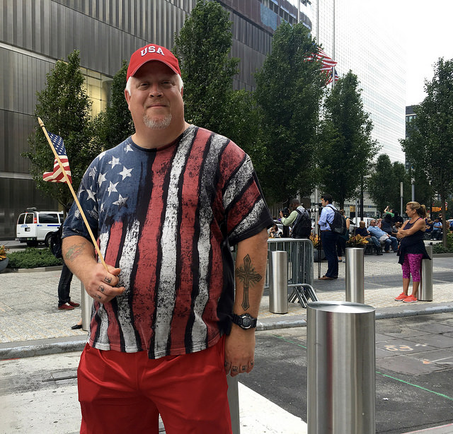 David Sears standing outside the 9/11 memorial waving his American flag. Photo by Jennifer Cohen